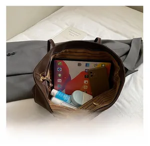 Spacious interior of brown tote bag showing a tablet, phone and makeup essentials