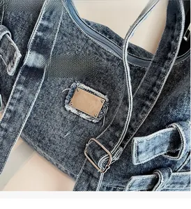 Vue détaillée du tissu denim vintage avec boucle argentée et plaque métallique gravée