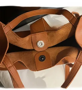Detail of magnetic buckle and lychee grain leather texture on brown tote bag