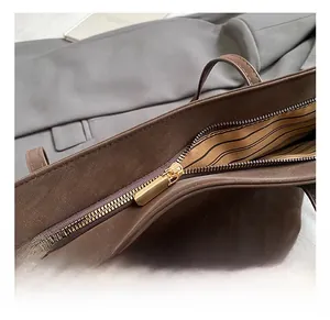Close-up of golden zipper hardware on a brown tote bag with striped fabric lining