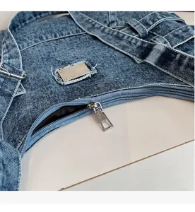 Gros plan sur la fermeture éclair et la plaque en métal du sac en jean bleu délavé