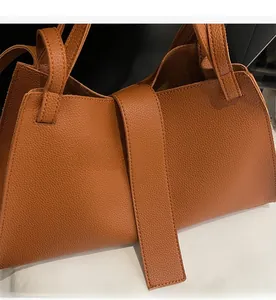 Close-up of brown pebbled leather texture and thick handle on a large hobo tote bag