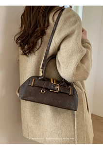Detail of dark brown leather handbag with retro buckle and gold hardware on model