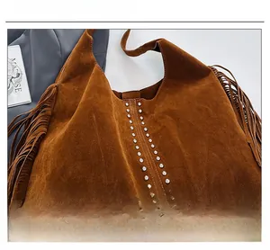 Close-up of brown suede tote bag featuring silver rivet studs and bohemian fringe details