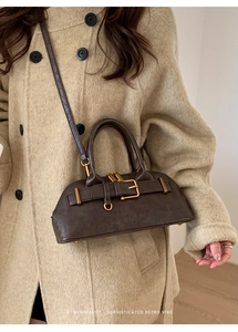 Close-up of minimalist retro brown leather bag with golden buckle on a wool coat