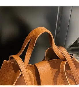 Detail of durable brown lychee-patterned leather texture and sturdy handles with stitching