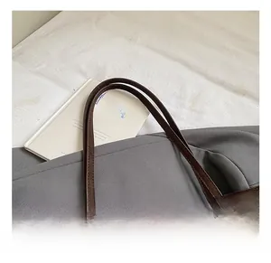 Detailed close-up of dark brown leather tote bag handle with reinforced stitching