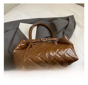 Close-up of brown quilted faux leather tote bag with glossy finish and buckle details