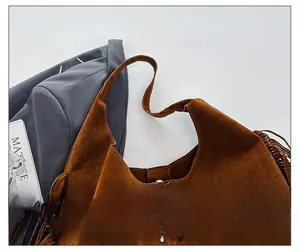 Close-up of brown suede tote bag featuring rivet details and stylish side fringe accents