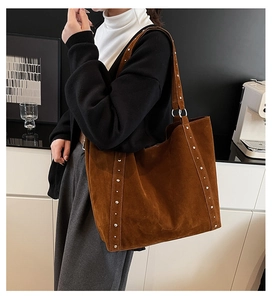 Sac cabas en daim marron avec clous argentés présenté dans un décor intérieur moderne