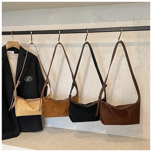Sacs hobo en daim en beige, marron et noir suspendus sur des crochets d'affichage