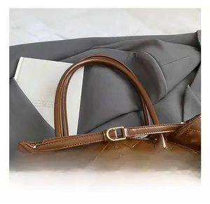 Detail of brown quilted oil wax leather tote with adjustable gold buckle and round handle