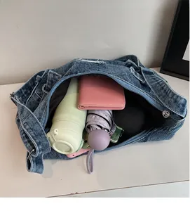 Vue intérieure montrant la grande capacité du sac à bandoulière en denim bleu