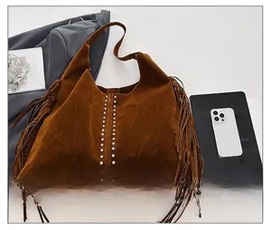 Macro detail of brown suede hobo bag with side tassels and silver metal rivets