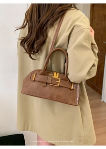 Brown shell bag shown as a shoulder bag on a model wearing a khaki trench coat