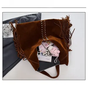 Detail view of large brown suede tote bag with fringe and studs showing spacious interior