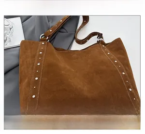 Détail du sac cabas vintage en daim marron avec rivets argentés et texture de tissu doux