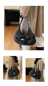 Détail du sac croissant en denim délavé gris foncé avec boucles métalliques et sangles