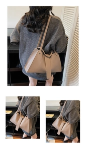 Close-up of minimalist light brown leather trapezoid handbag with pebbled texture and wide strap