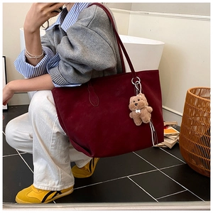 Detail of burgundy vintage tote bag featuring soft suede texture and a cute bear charm