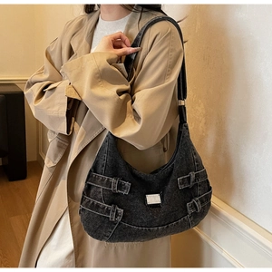 Detail of grey denim hobo bag featuring silver buckles and industrial style straps