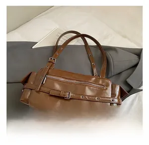 Detailed view of brown vintage leather bag with decorative buckles and metal eyelets