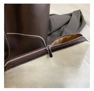 Close-up of canvas bucket bag with brown leather trim and silver zipper hardware