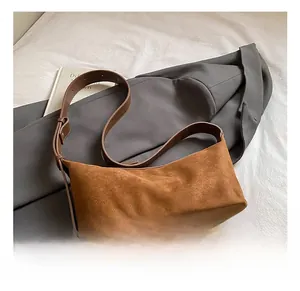 Détail de la surface en daim marron et de la bandoulière réglable du sac à bandoulière