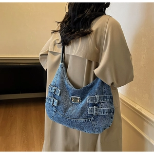 Vue latérale du grand sac hobo en jean bleu avec plaque en métal et sangle ajustable