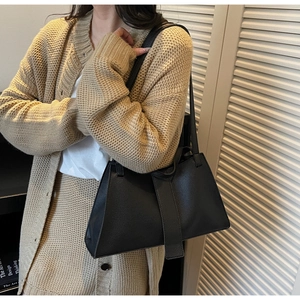 Detail of black pebbled leather hobo bag worn with beige cardigan for casual styling