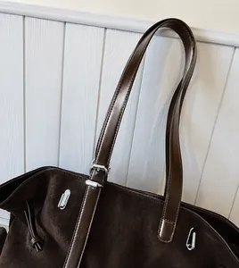 Détail du sac cabas marron foncé montrant la texture mate et la boucle ajustable de l'anse