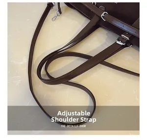 Détail d'un sac cabas en daim marron foncé avec bandoulières réglables et boucles argentées