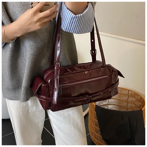 Detail of burgundy patent leather bag showing functional pockets and glossy texture