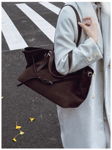 Détail du sac fourre-tout en daim marron foncé avec bandoulière et anneaux en métal
