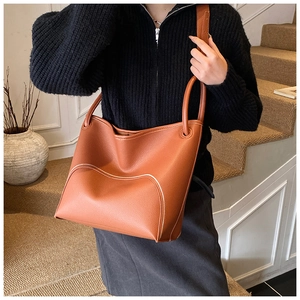 Close-up of brown pebbled leather bucket bag featuring elegant white contrast stitching detail
