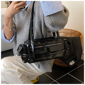 Detail of glossy black underarm bag with silver hardware and functional utility pockets