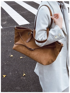 Détail du sac cabas en daim marron foncé avec lanières en cuir sur modèle en manteau blanc