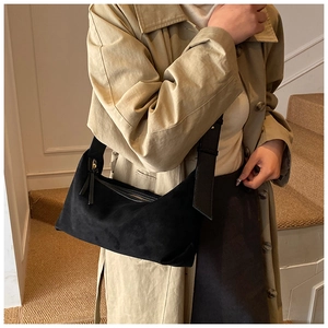 Gros plan du sac hobo en daim noir minimaliste avec large bandoulière et zip métallique