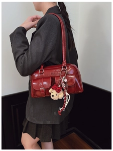 Détail du sac bandoulière en cuir verni rouge avec poches et charmant porte-clés ours