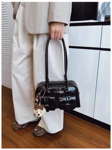 Détail du sac sous le bras noir brillant avec poches à boucle et breloque chiot en peluche
