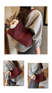 Details der burgunderroten Ledertasche mit weißen Kontrastnähten und Hasenanhänger