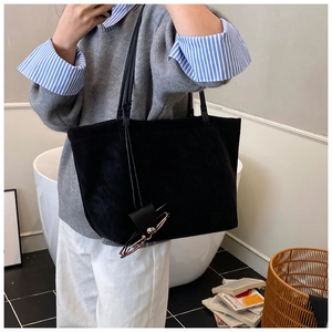 Detail view of large black suede tote bag with glasses hanger accessory for commute