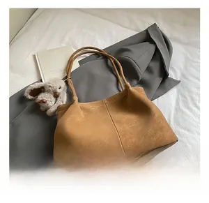 Detail einer großen braunen Shopper-Tasche aus Wildlederimitat mit flauschigem Hasen-Anhänger