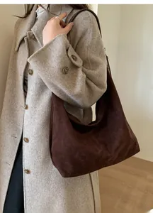 Brown suede hobo bag on shoulder of woman wearing a beige wool coat for fall fashion