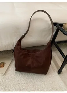 Detail of minimalist dark brown suede hobo bag with adjustable thick leather strap