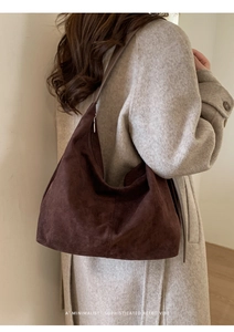 Detailed texture of brown suede tote bag featuring a wide shoulder strap and metal zipper