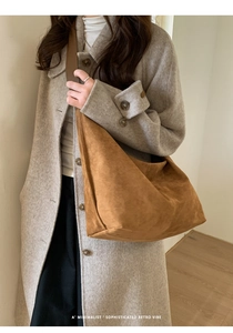 Brown faux suede hobo bag on shoulder showing large capacity and soft drape texture
