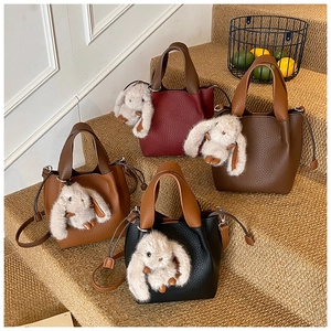 Détail de quatre sacs seaux colorés en cuir grainé avec breloques de lapin en peluche