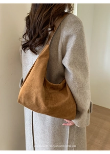 Brown suede hobo bag shown from a side view with a wide shoulder strap and minimal design