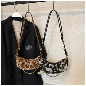 Detailed close-up of cow pattern crescent hobo bags with golden chain and knot strap
